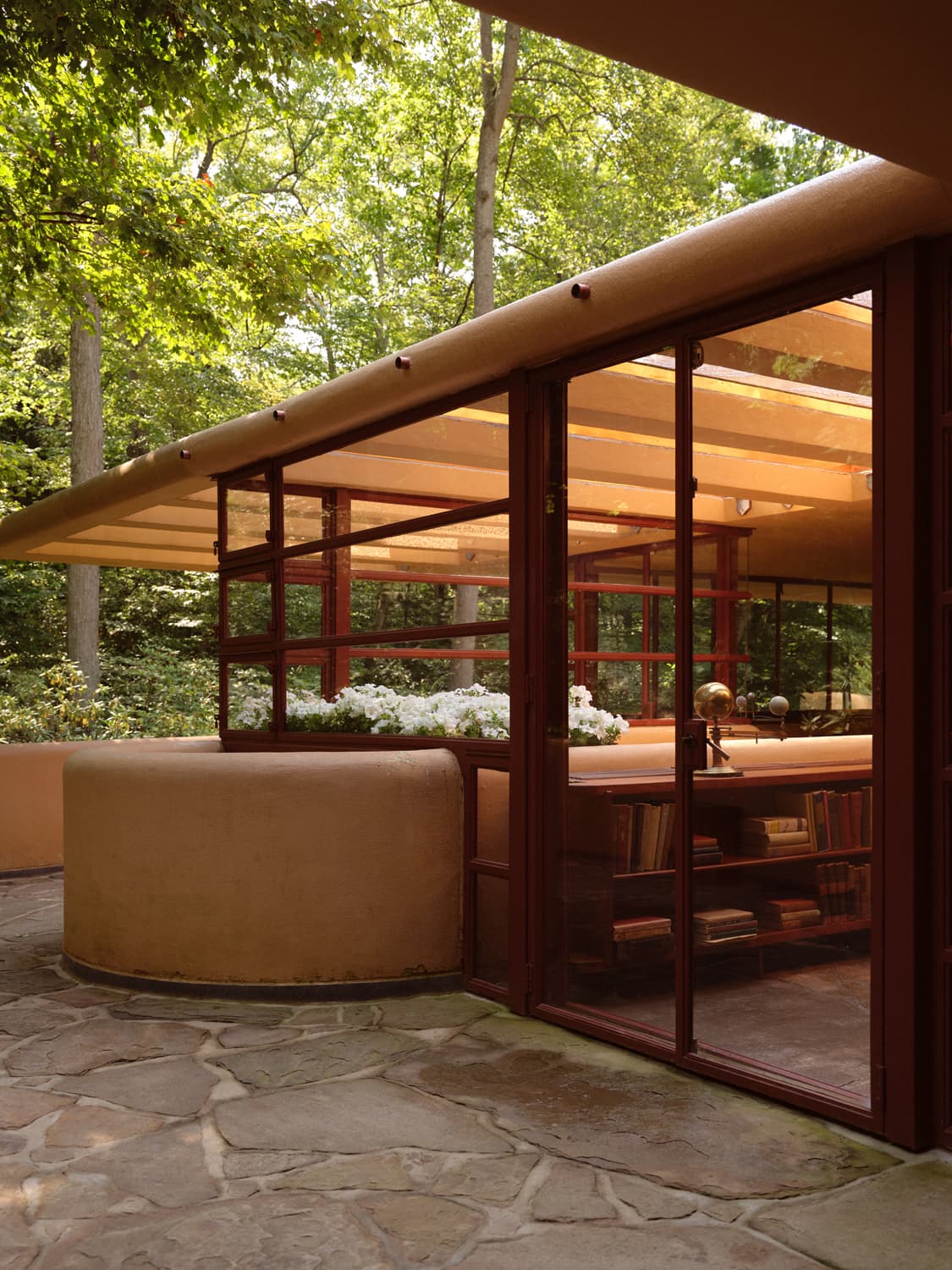 Fallingwater terrace looking into the living room through glass doors with built in bookshelves