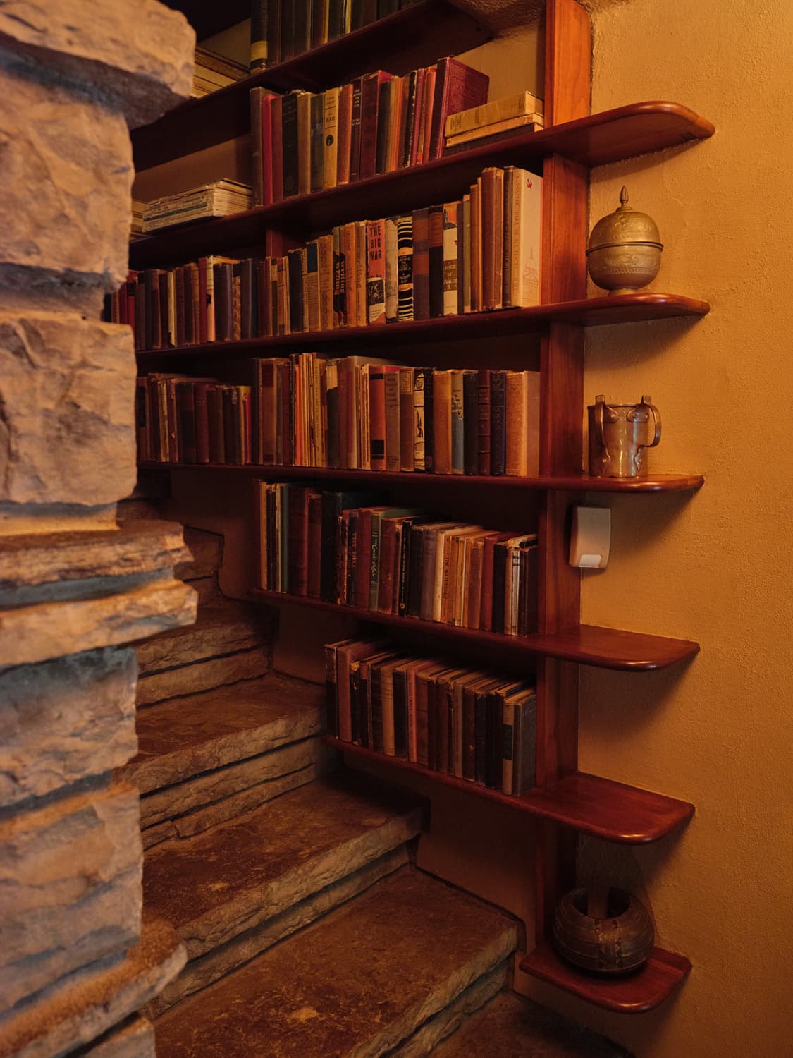Built in walnut bookshelves filled with vintage books tucked into a stone alcove at Fallingwater